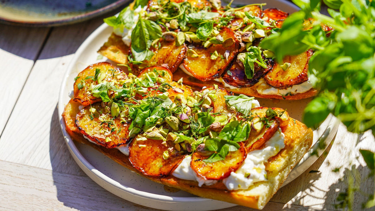 Rostat surdegsbröd med stekt persika, burrata, honung & pistagenötter