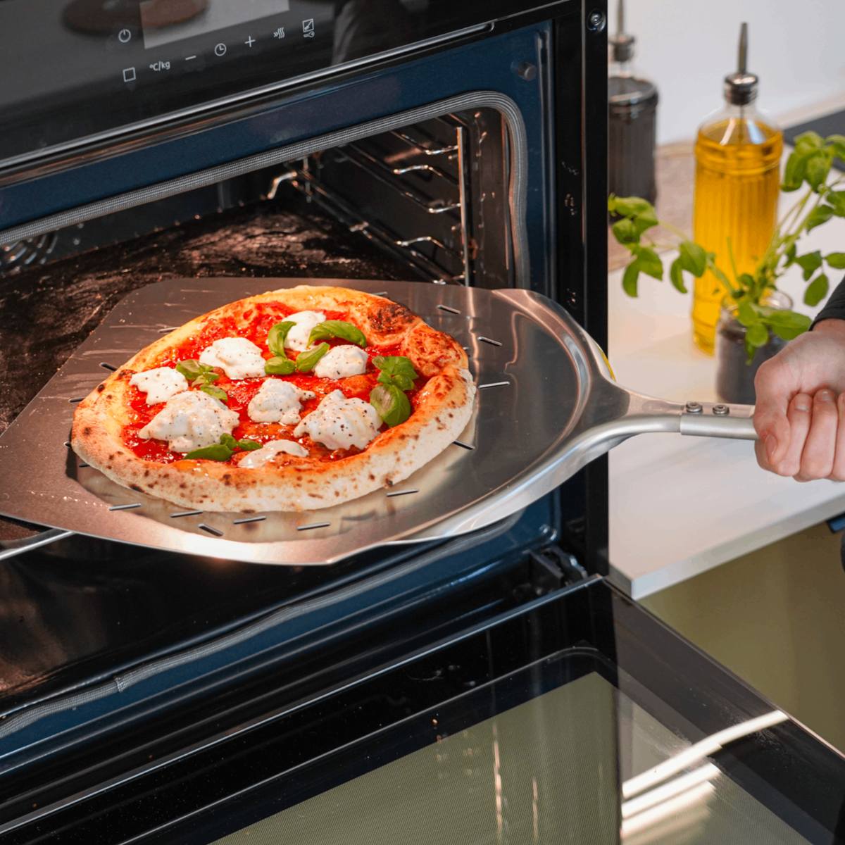 Pizzaspade med pizza i ugnen